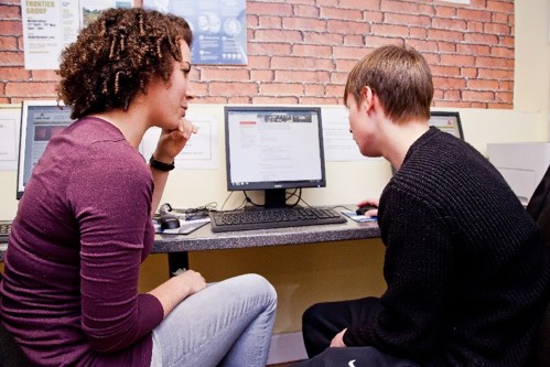 A couple of people looking at a computer

Description automatically generated